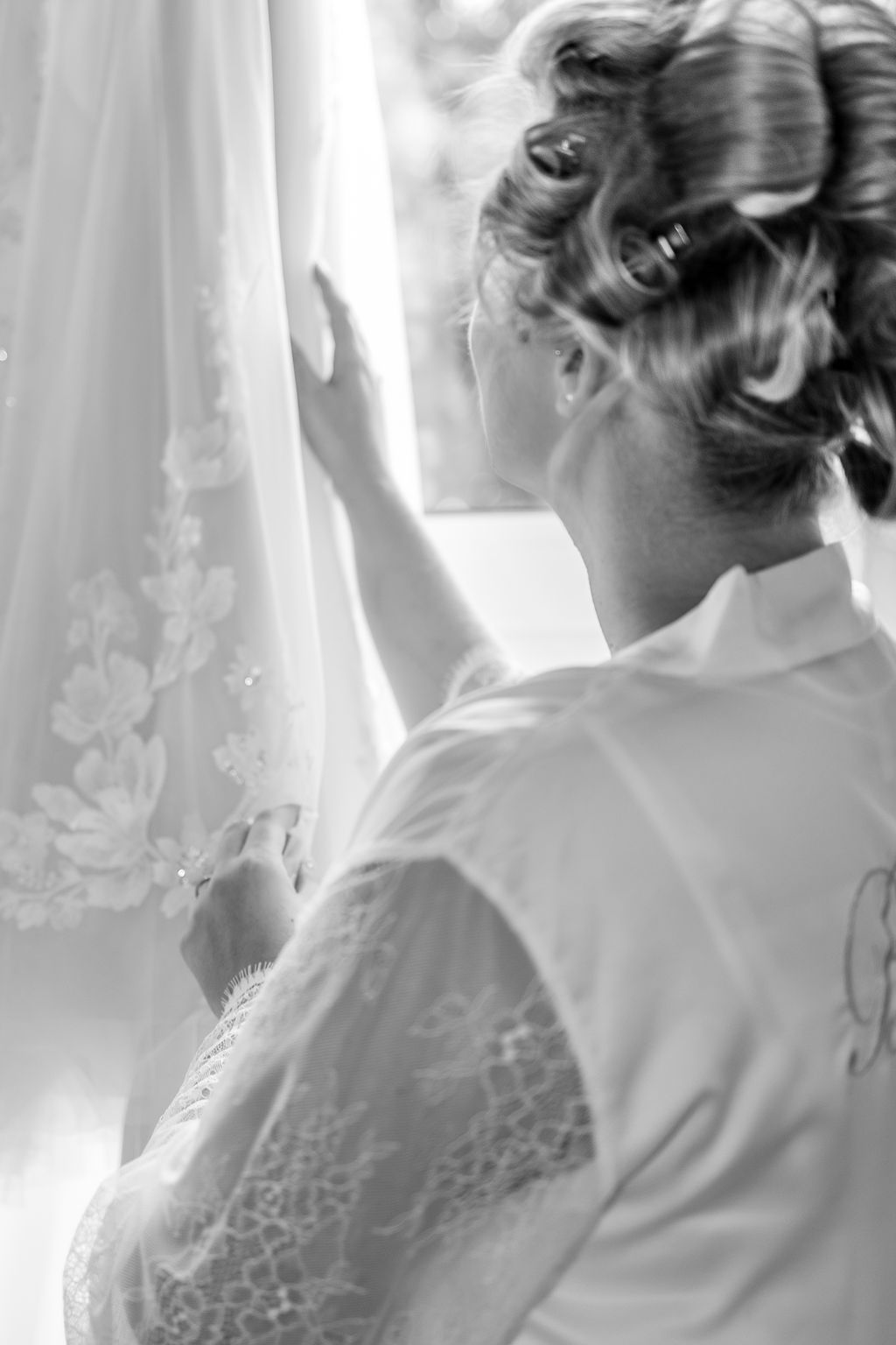 Eine Person in einem Morgenmantel blickt auf ein Brautkleid mit Spitze, Hochzeitsvorbereitungen.