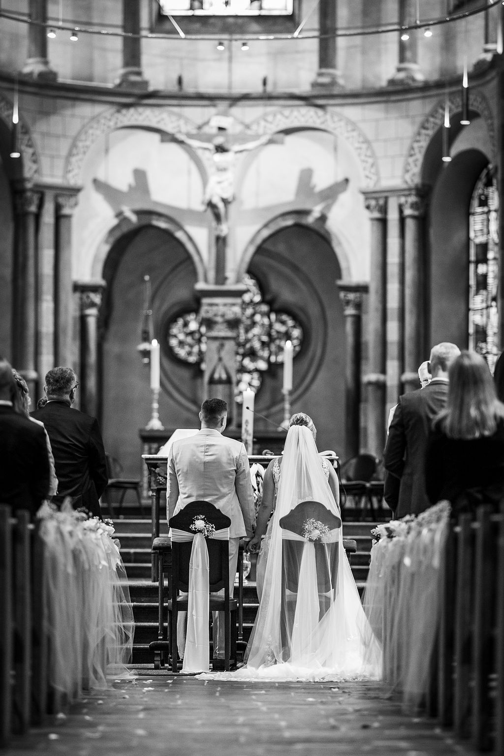 Brautpaar in einer Kirche, von hinten gesehen, während der Trauung.