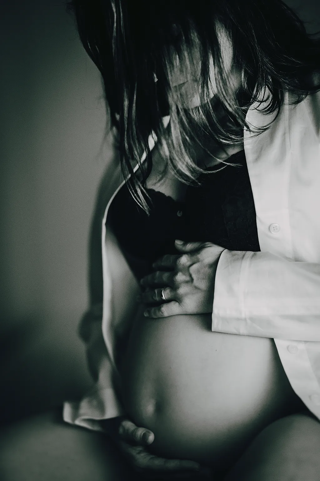 Eine schwangere Frau, die ihr Babybauch hält, in Schwarz-Weiß.
