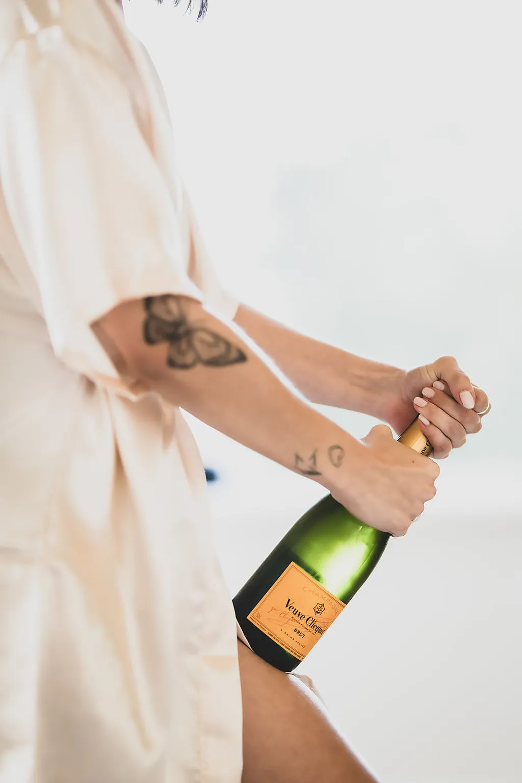 Eine Person in einem Morgenmantel öffnet eine Flasche Champagner.