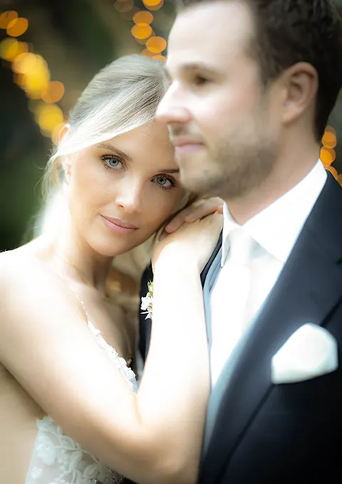 Nahaufnahme eines Brautpaares, die Braut lehnt ihren Kopf an die Schulter des Bräutigams. Bokeh im Hintergrund.