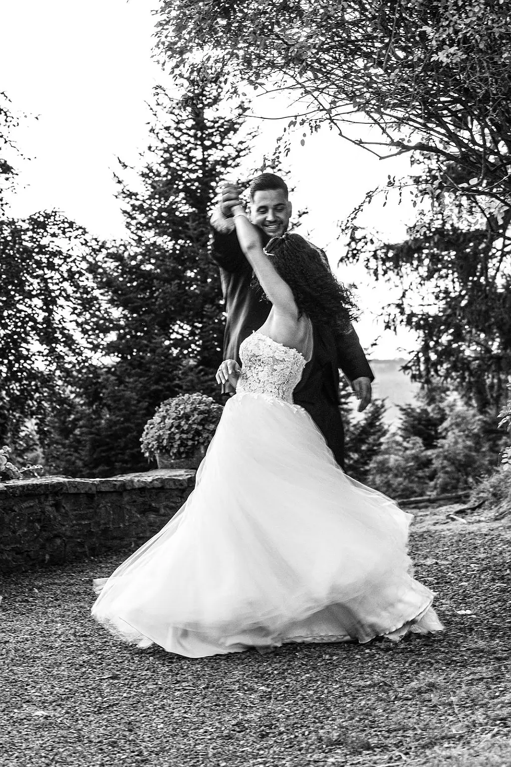 Ein Hochzeitspaar tanzt, die Braut in einem bodenlangen Hochzeitskleid mit Schleier oder Tüll, der Bräutigam in einem Anzug.