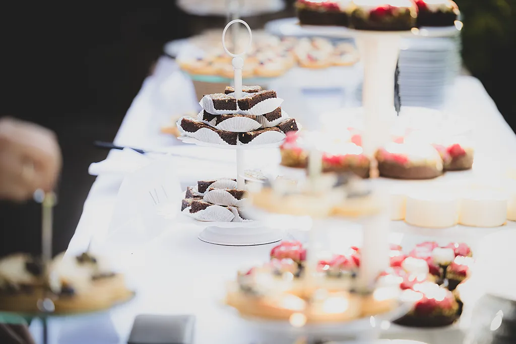 Eine Etagere mit Brownies und weiteren Süßigkeiten auf einem Buffet, unscharf im Vorder- und Hintergrund.
